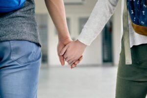 Couple holding hands in corridor, cropped